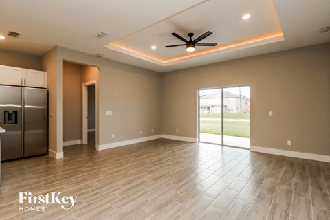 a empty living room with a kitchen and a ceiling fan