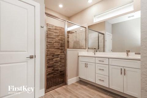 a bathroom with white cabinets and a shower and a sink