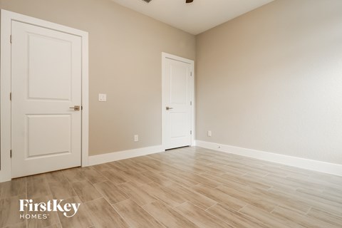 a bedroom with two doors and a hardwood floor