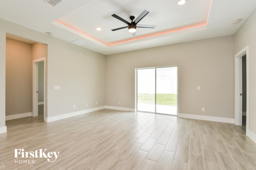 an empty living room with a ceiling fan and wood floors