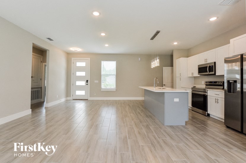 an empty kitchen with stainless steel appliances and wooden floors