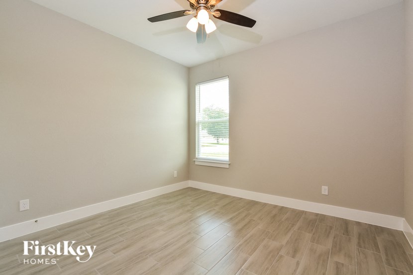 an empty room with a ceiling fan and a window