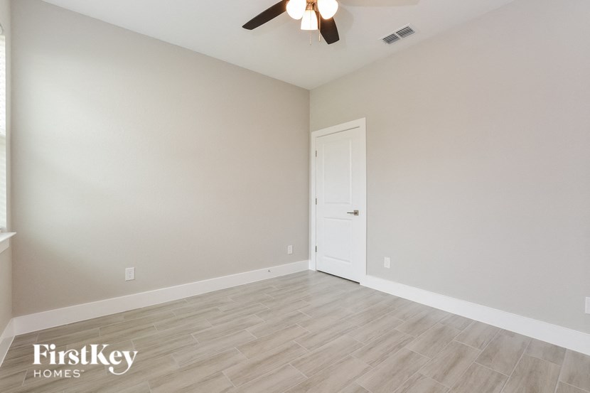 an empty living room with a ceiling fan and a door