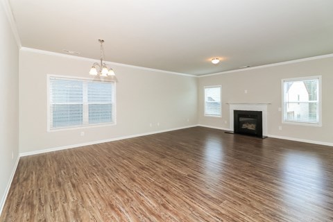 an empty living room with a fireplace and wooden floors