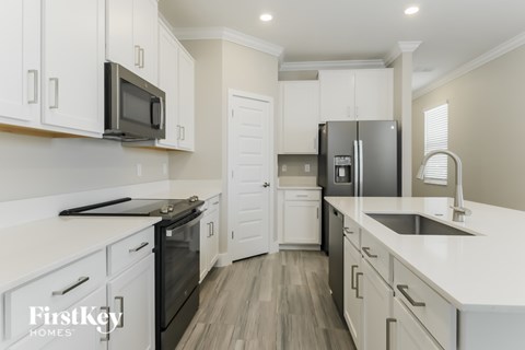 A kitchen with white cabinets and a black fridge.