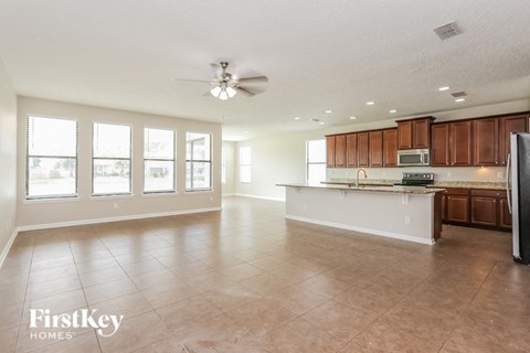 A spacious kitchen and living room with a refrigerator on the right.
