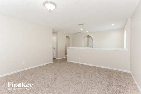 A spacious empty room with a carpeted floor and a window.