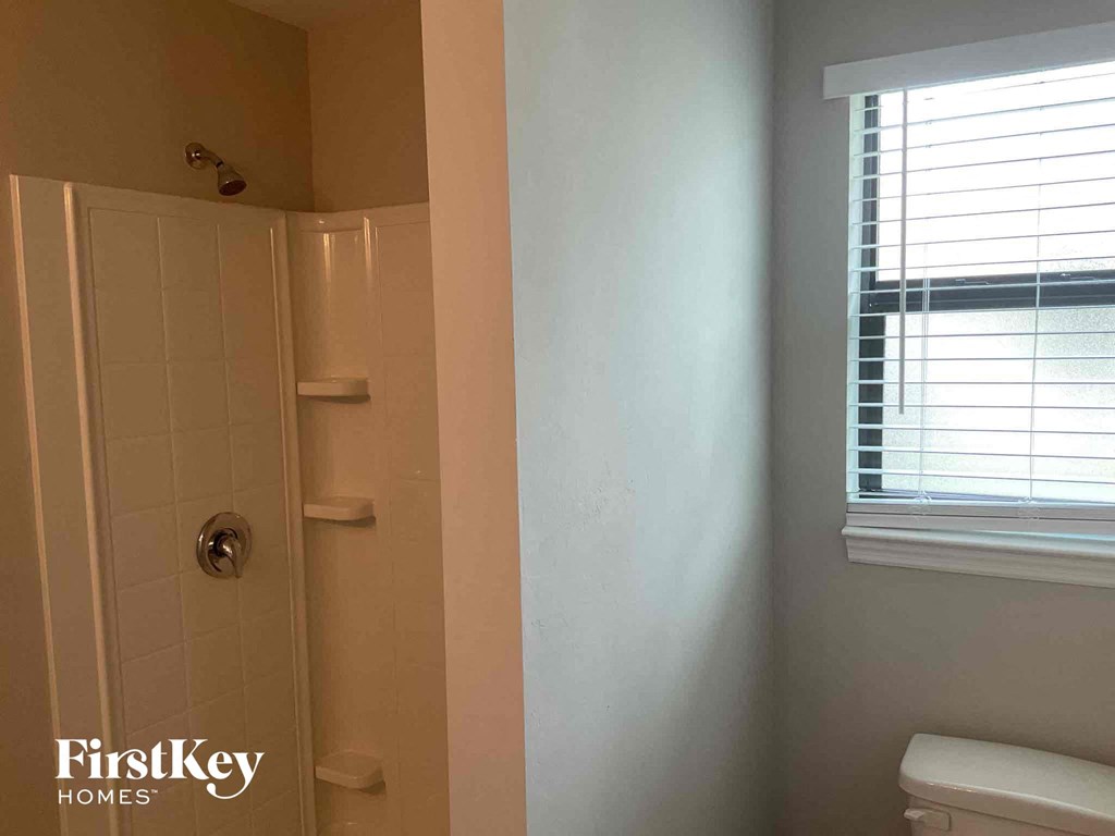 a bathroom with a shower and a toilet and a window