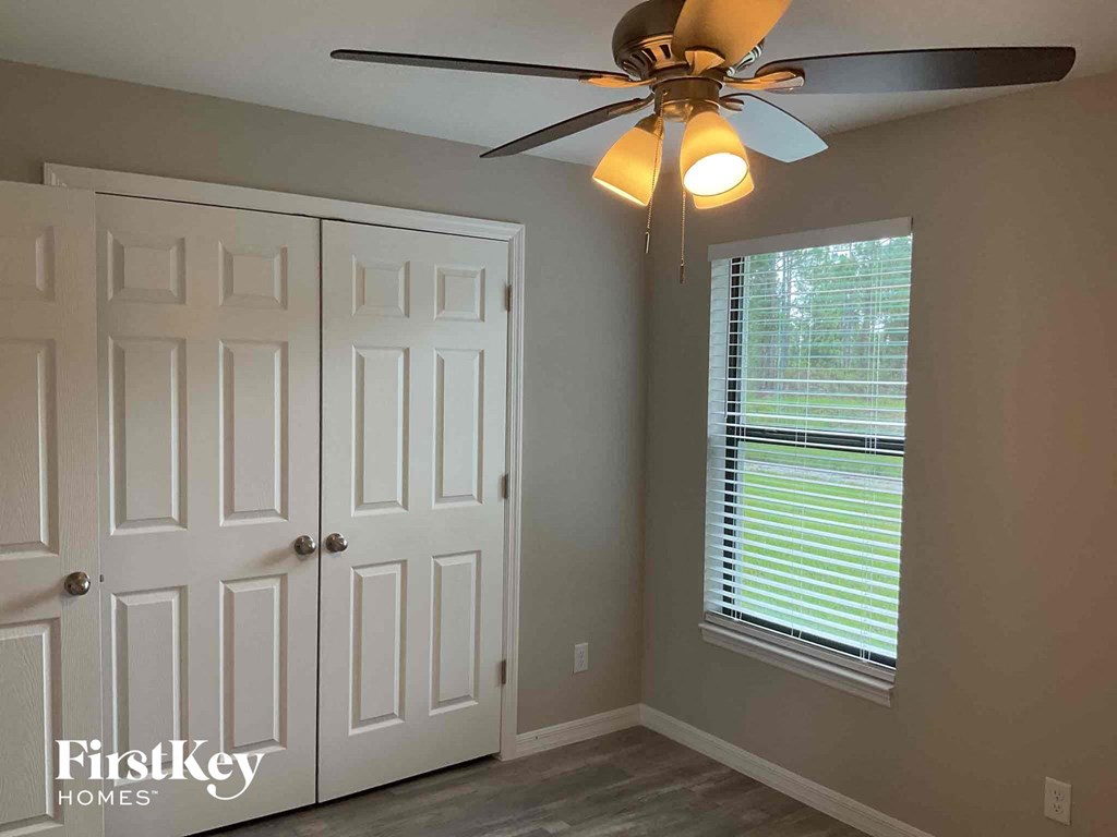 a bedroom with a ceiling fan and a door and a window