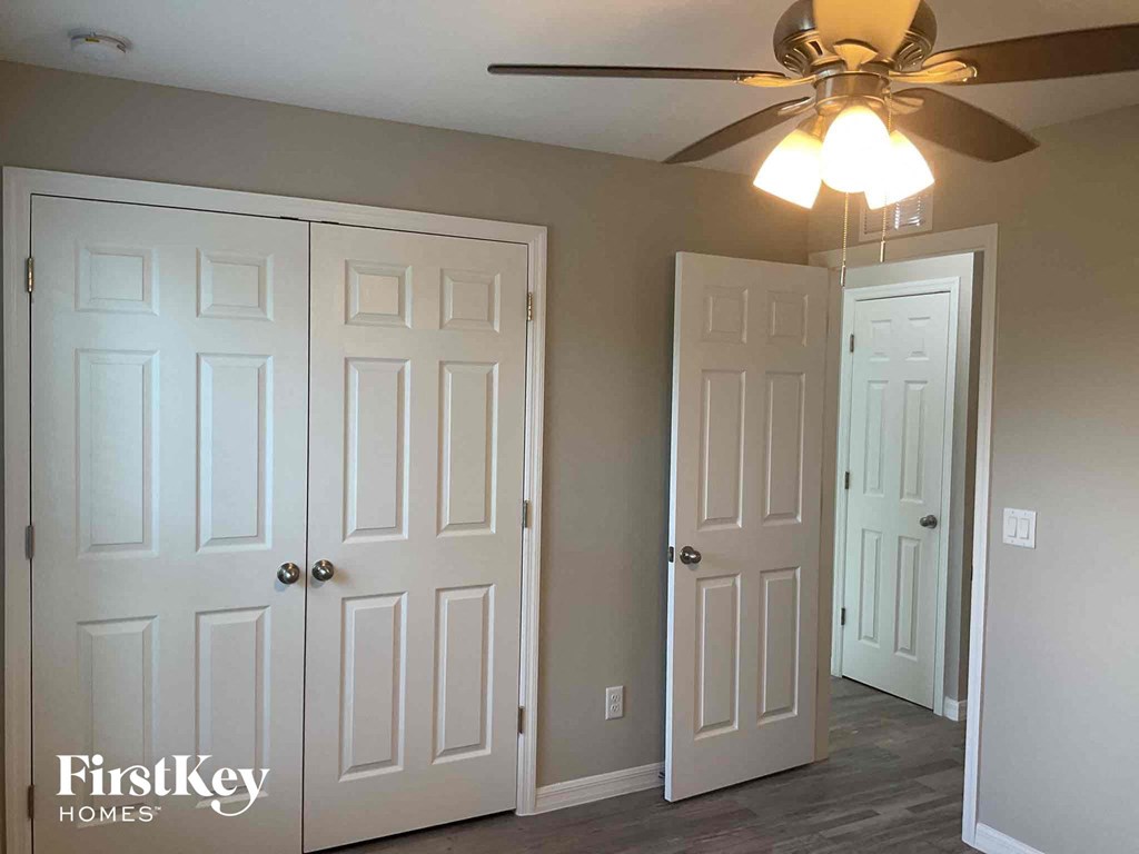 a bedroom with two closet doors and a ceiling fan