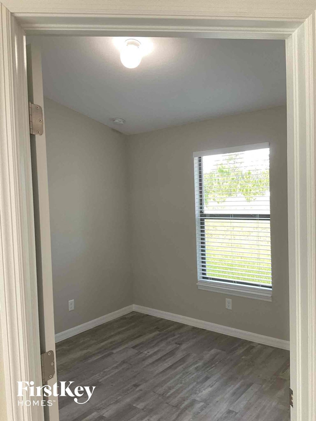 a small room with a window and a wooden floor