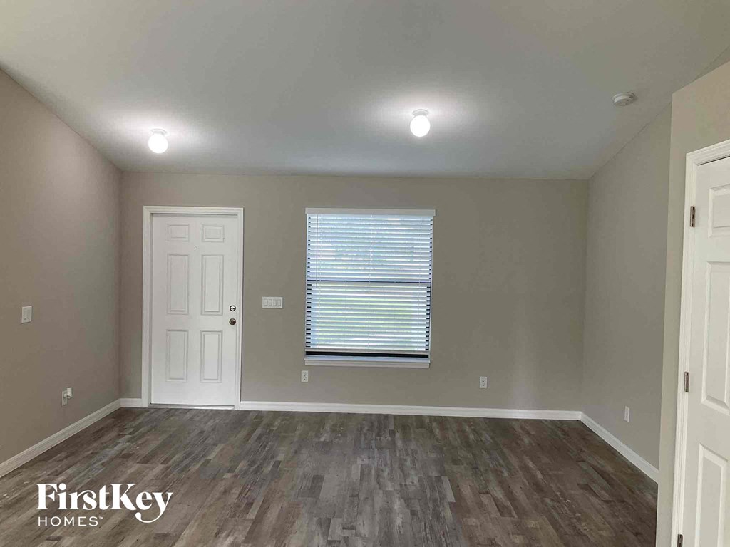 an empty living room with wood floors and a window