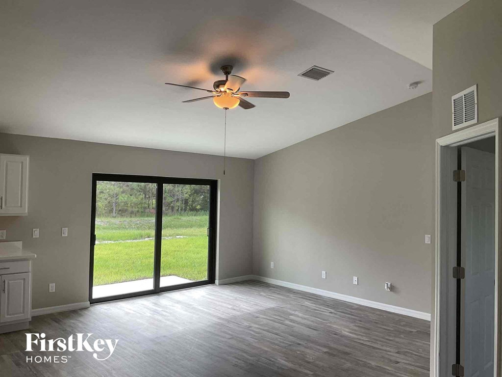 an empty living room with a ceiling fan and a sliding glass door