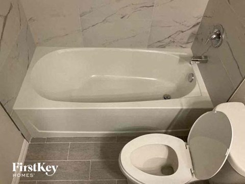 A white toilet is next to a bathtub in a bathroom.