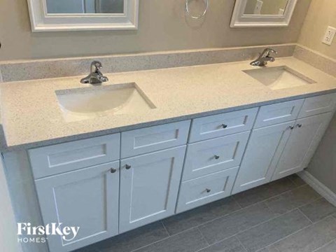 A bathroom with two sinks and white cabinets.