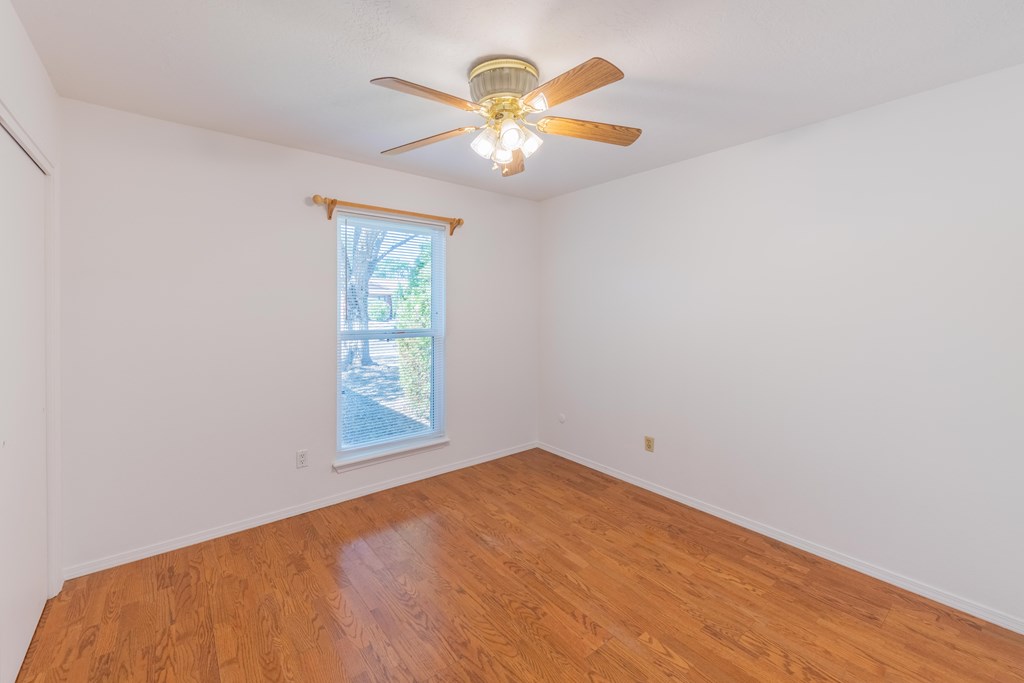 an empty room with a ceiling fan and a window
