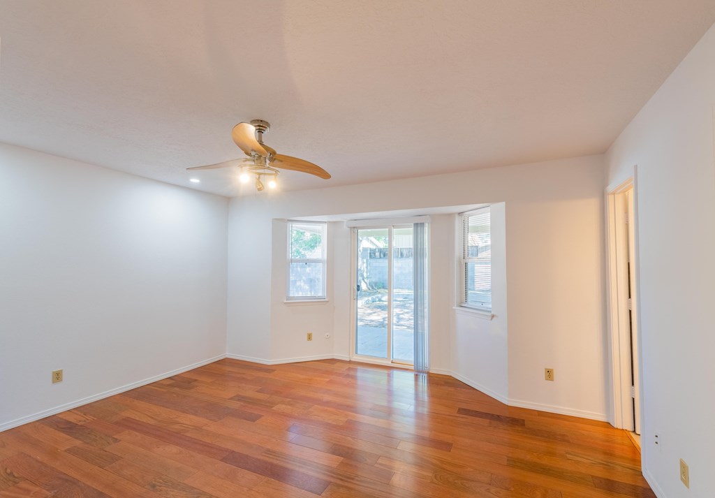 an empty living room with a ceiling fan and wood floors
