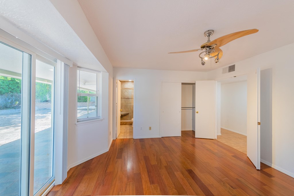 a living room with wood floors and a ceiling fan
