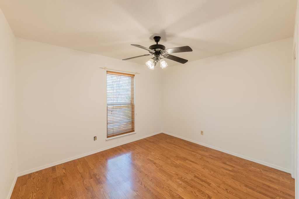 an empty living room with a ceiling fan and wood floors