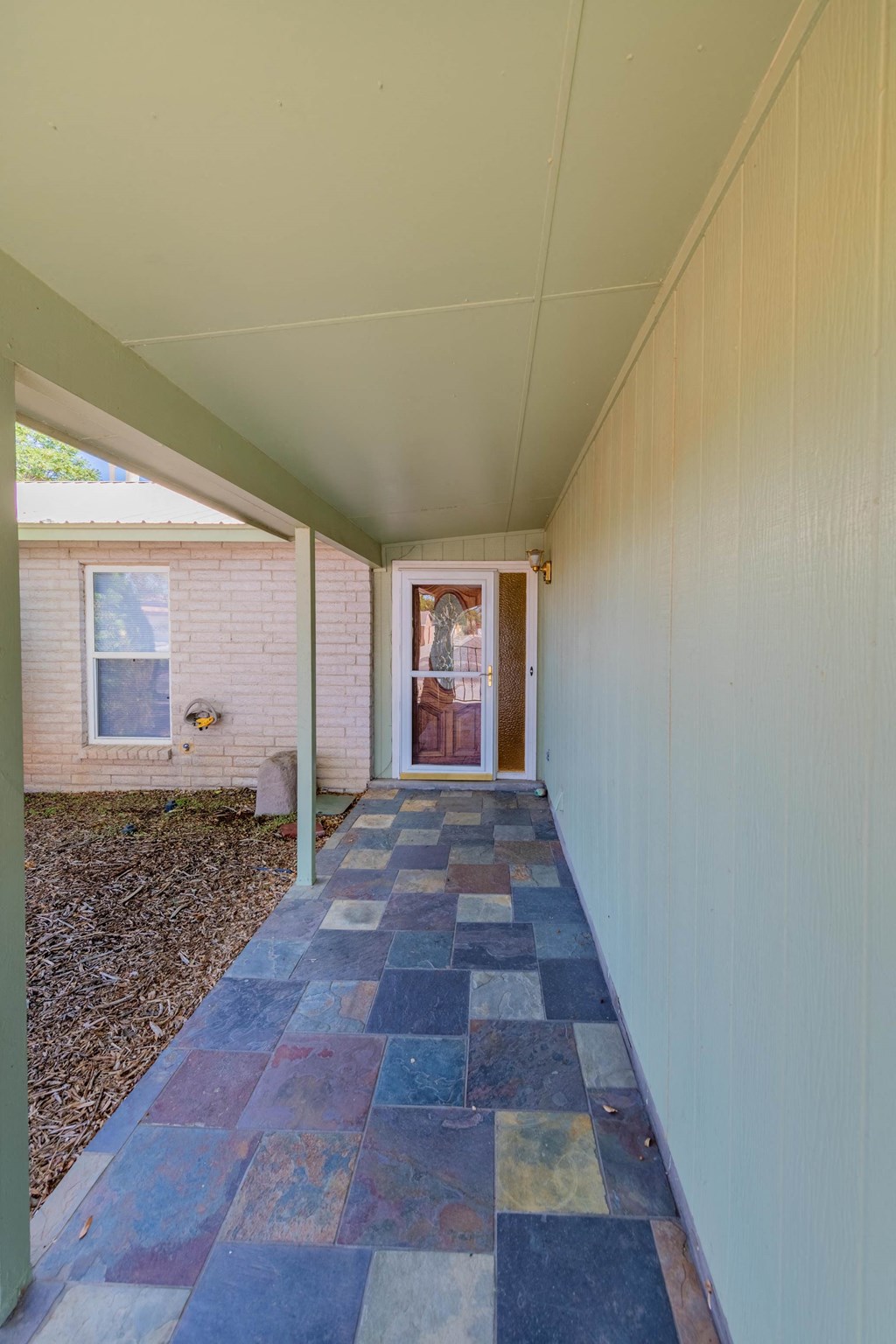 a long porch with a tiled floor in front of a house