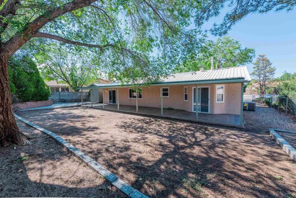 a small pink house with a driveway and a tree