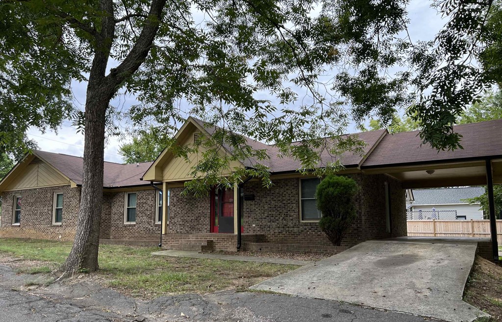 A house with a red door is surrounded by trees.