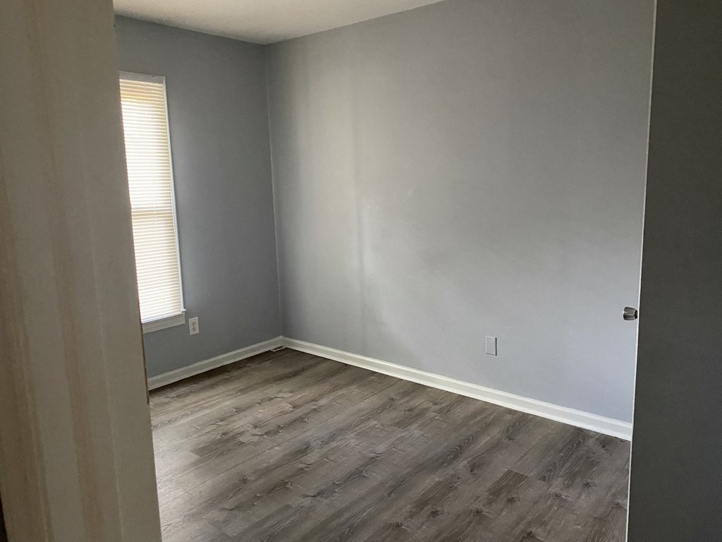 A room with a grey wall and a wooden floor.