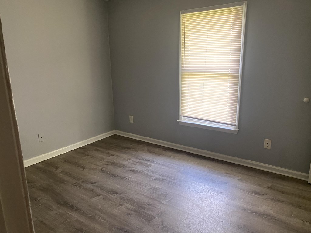 A room with a window and wooden flooring.