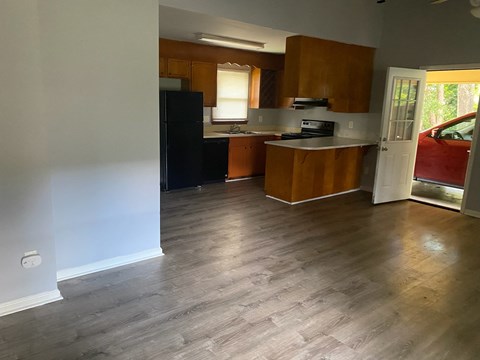A kitchen with wooden cabinets and a black fridge.