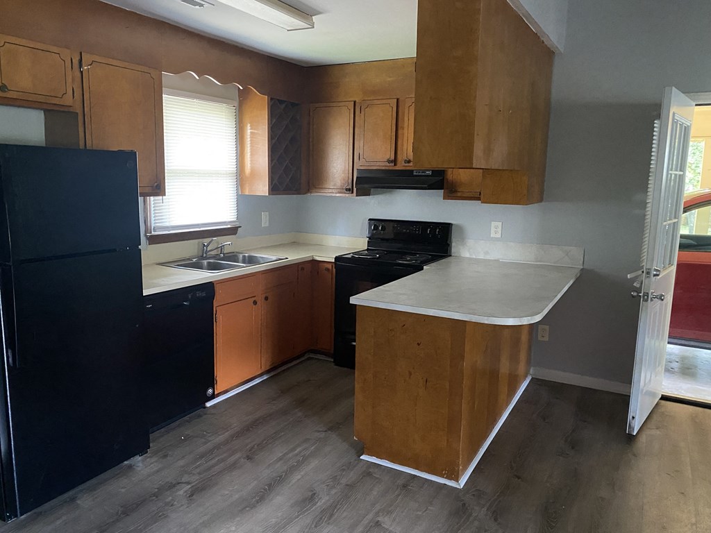 A kitchen with wooden cabinets and a black fridge.