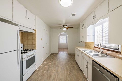 an empty kitchen with white cabinets and stainless steel appliances