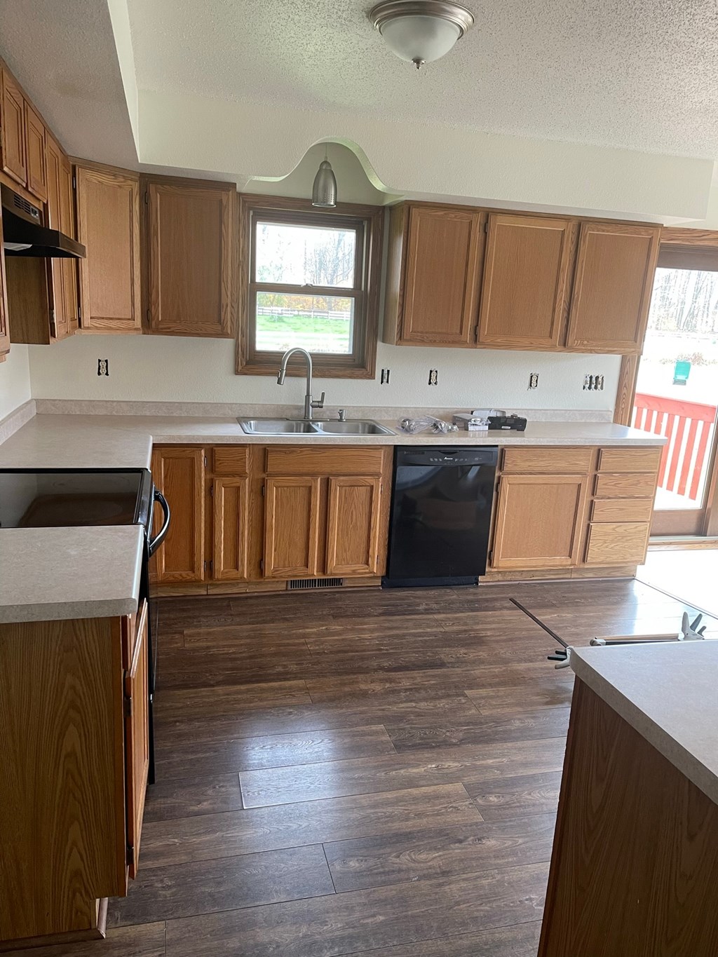 an empty kitchen with wooden cabinets and a black dishwasher