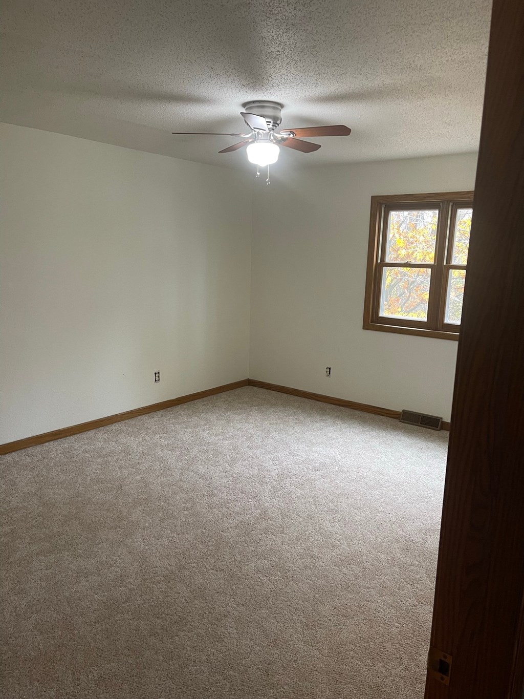 an empty room with a ceiling fan and a window