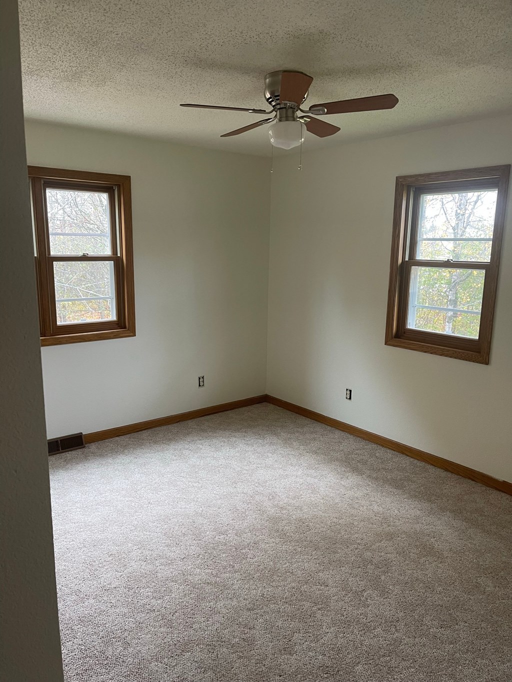 an empty room with a ceiling fan and two windows