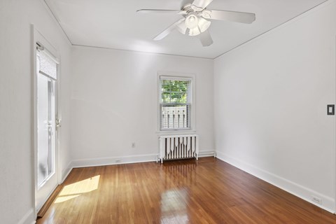 A room with a ceiling fan and a window with a view of trees.