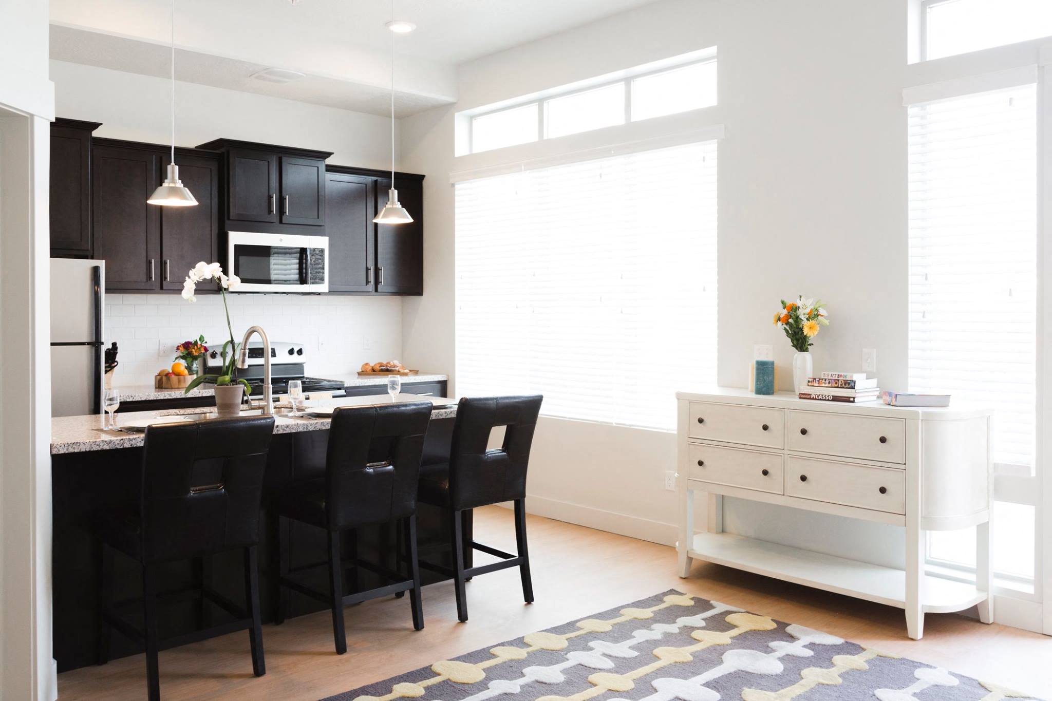 A kitchen with black chairs and a white counter.