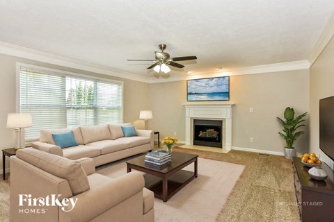 A living room with a beige couch, a coffee table, a fireplace, and a painting on the wall.