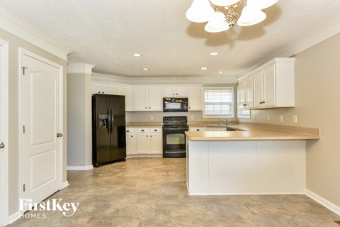 A kitchen with a black refrigerator and white cabinets.