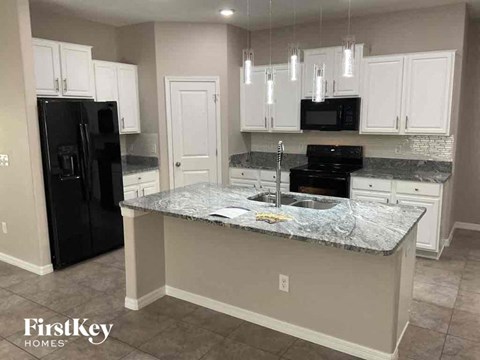 A kitchen with granite countertops and a black refrigerator.
