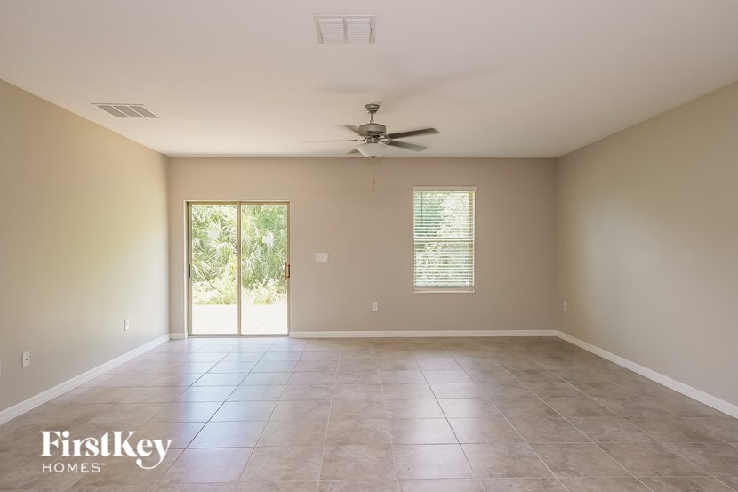 A spacious room with a ceiling fan and sliding glass doors leading to a patio.