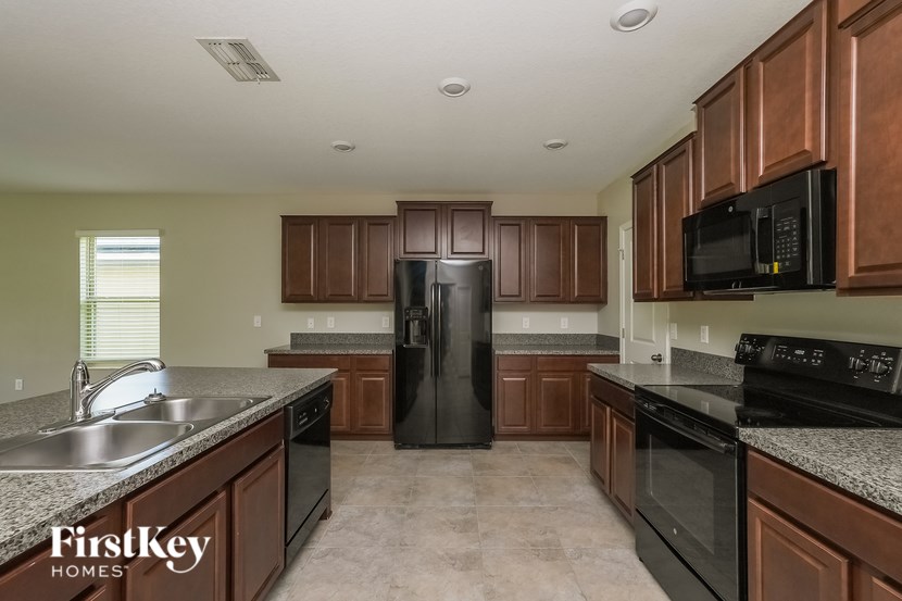 A kitchen with brown cabinets and black appliances.