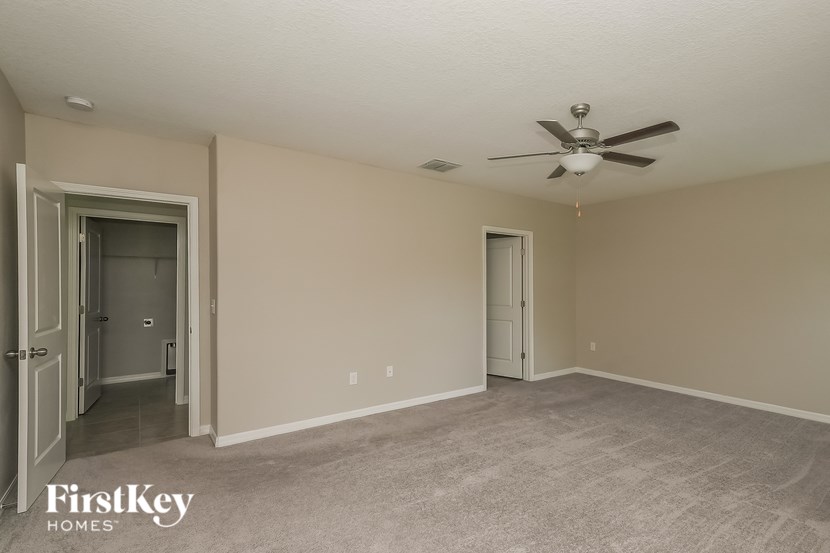 A spacious room with a ceiling fan and two doors.