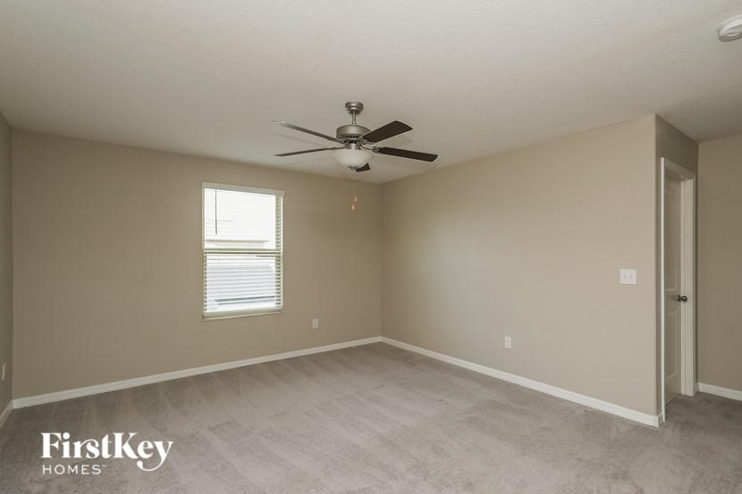 A room with a ceiling fan and a window with blinds.
