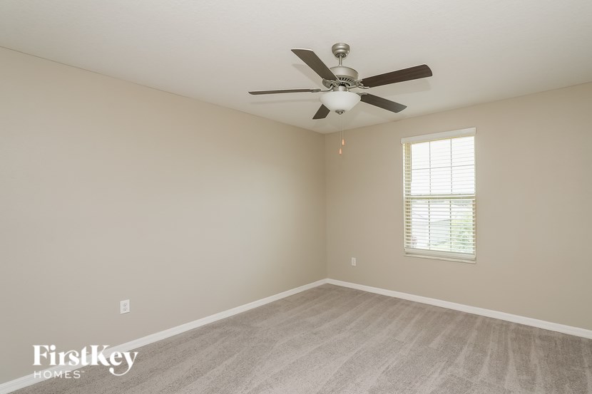 A room with a ceiling fan and a window with blinds.