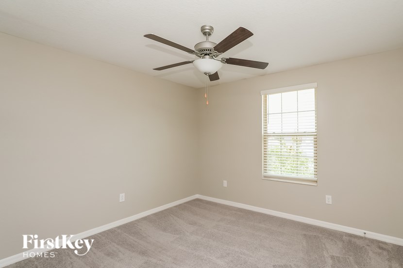 A room with a ceiling fan and a window with blinds.