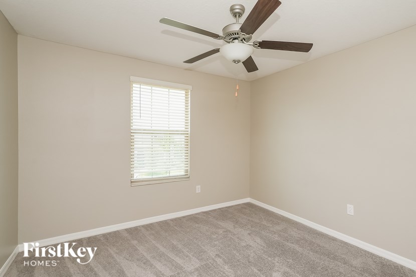 A room with a ceiling fan and a window with blinds.