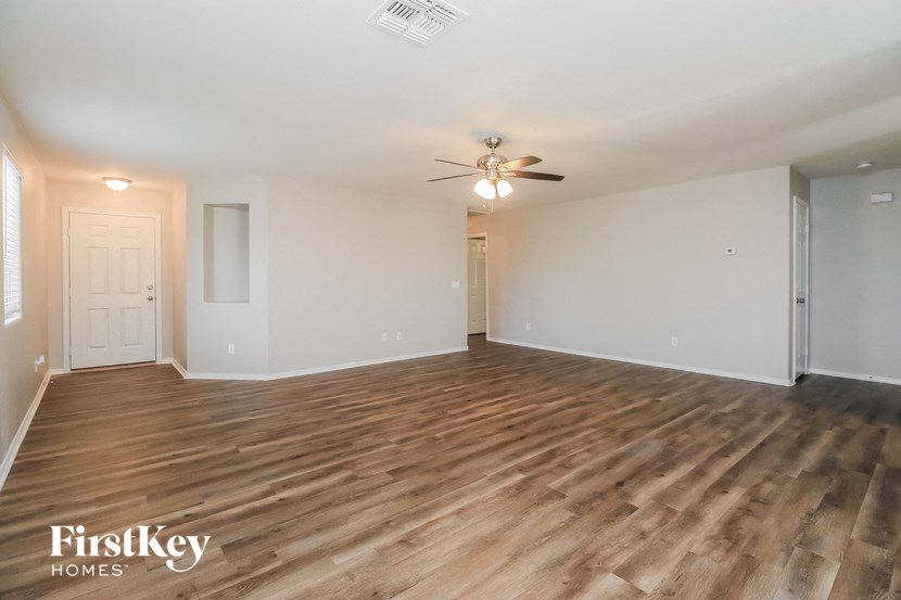 an empty living room with wood flooring and a ceiling fan