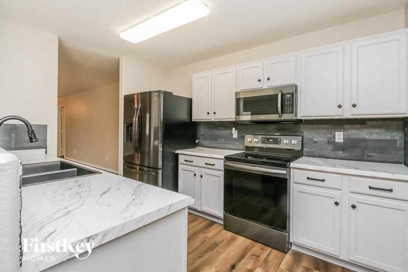 a kitchen with white cabinets and black appliances