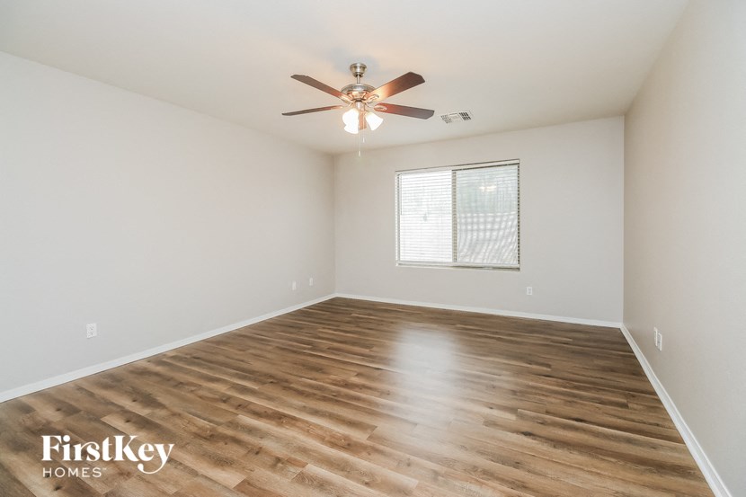 the spacious living room with hardwood flooring and a ceiling fan