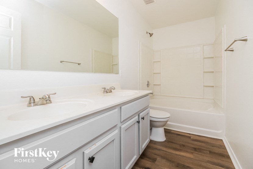 a bathroom with white cabinets and a white toilet and a sink